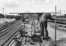 841114 Afbeelding van een monteur van N.S. op het dak van het electrische treinstel nr. 757 (mat. 1954, plan G) op het ...